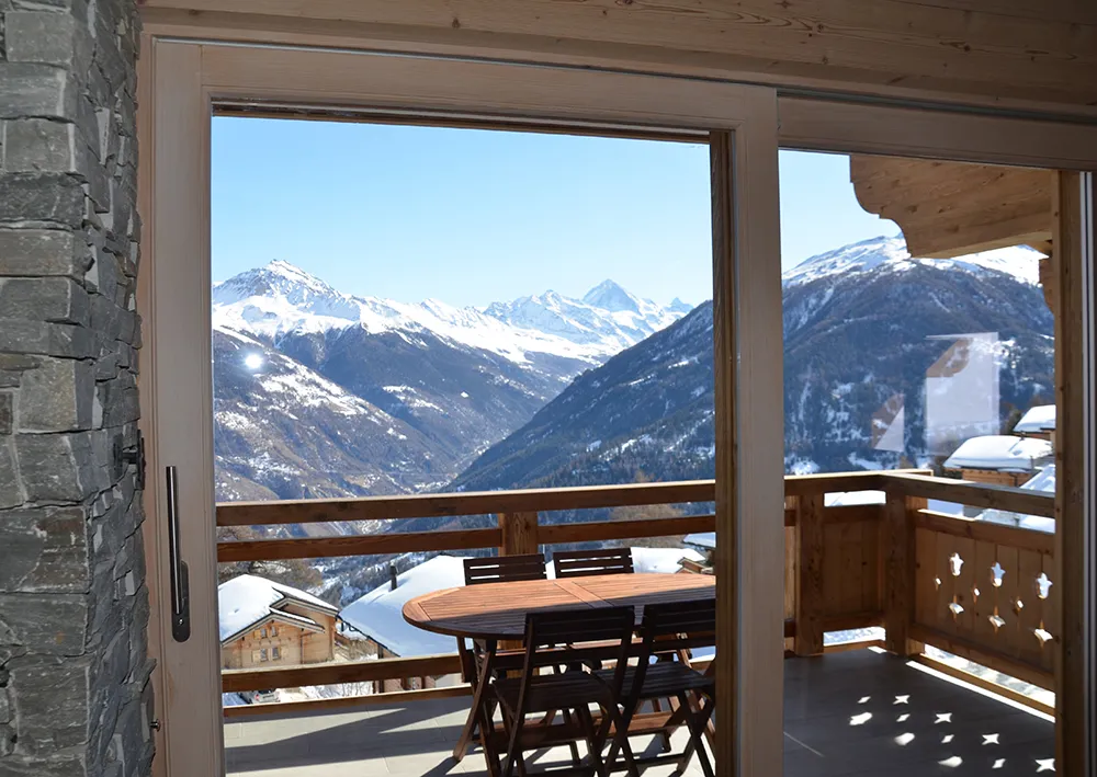 Terrasse d'un chalet face aux sommets enneigés